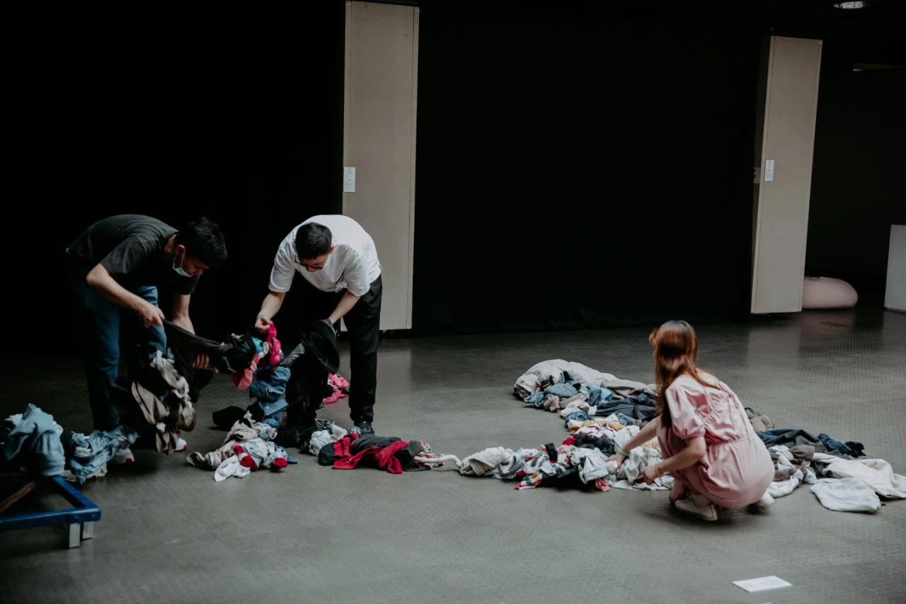 Three people handling the clothes on the floor